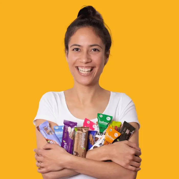 Glückliche Frau mit foodloose Snacks vor Hauswand